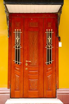 Brown decorated door with doorstep against the yellow wall background