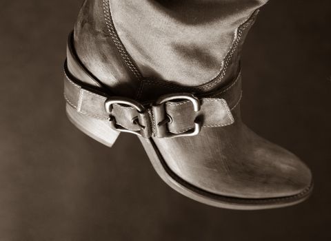 Female boot of the cowboy on a dark background