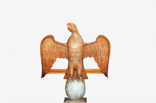 A photograph of a wooden carved eagle positioned on a large egg, taken in an English Cathedral