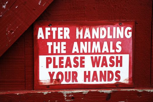 A farm sign telling people who have handled the animals to wash their hands