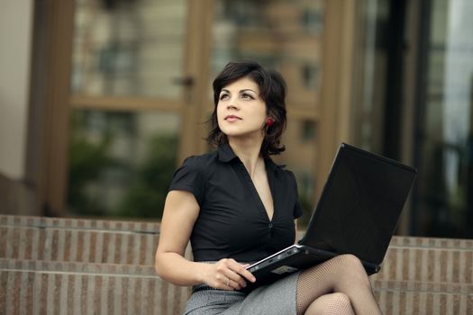 young attractive business woman with the laptop outdoors looking up