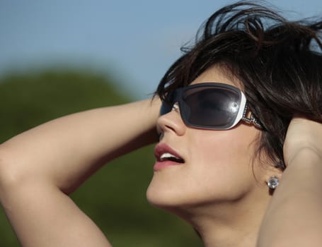 profile view of a beautiful young lady with dark sun glasses outdoor looking at the sun smiling