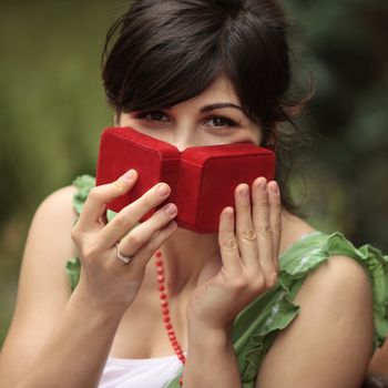 happy young lady playing with a red gift box by covering her face with it