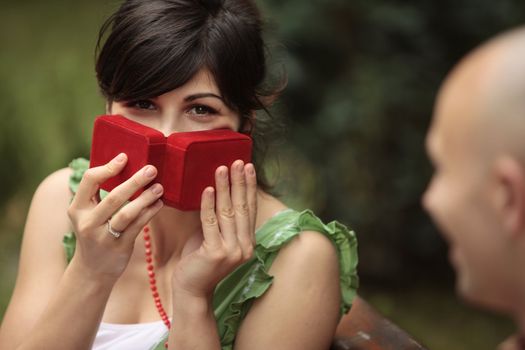 happy young lady playing with a red gift box by covering her face with it