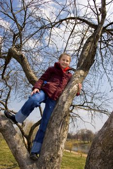 Girl will climb on tree. City park. Spring time.