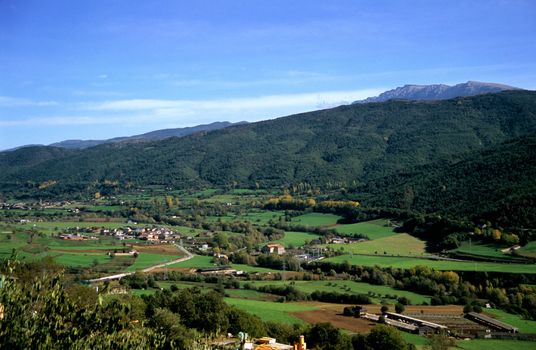 Villages and farms sit in a valley in the Pyrenees mountain range in Spain.