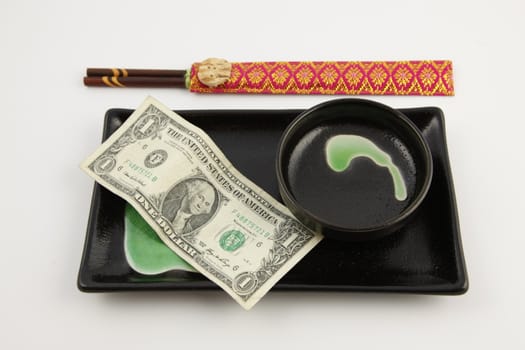 One United States dollar bill on a sushi plate with chopsticks with a white background