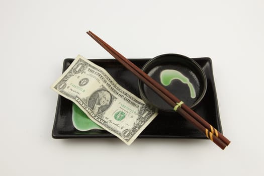 One United States dollar bill on a sushi plate with chopsticks on a white background