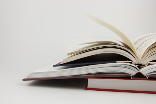 Two open books on a third closed book with a white background