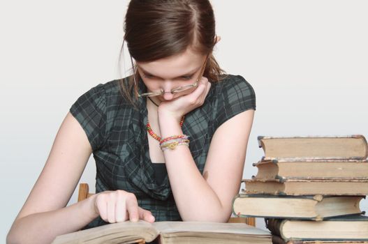 Nice young reading girl near stack of old books