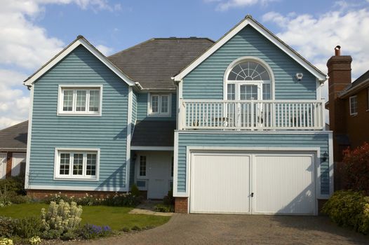 A blue wooden clad house with a cloudy sky