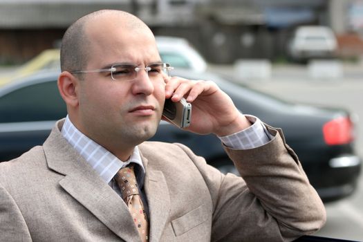 businessman calling by mobile phone, around a luxurious car