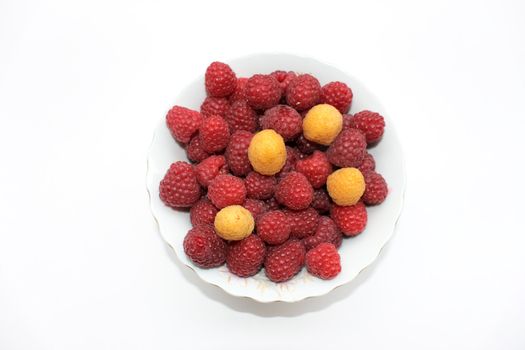 Red and yellow raspberries in the bowl, isolated