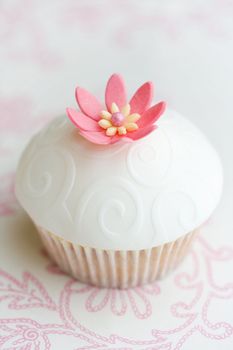 Cupcake decorated with embossed fondant and a pink sugar flower