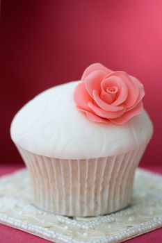 Cupcake decorated with embossed fondant and a pink sugar rose