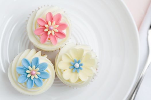 Three flower cupcakes on a white plate