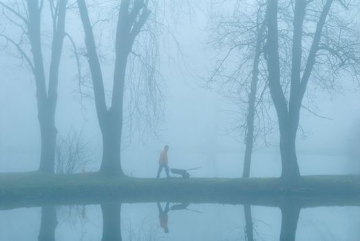 The gardener on coast of lake. Earlier morning. A fog