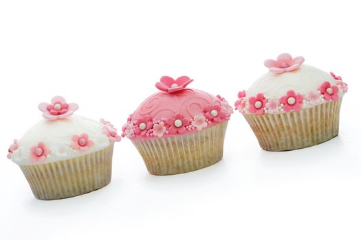 Three pink and white cupcakes against a white background