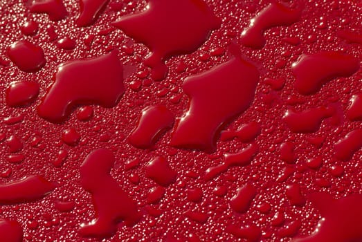 Raindrops on a red surface. A close up.