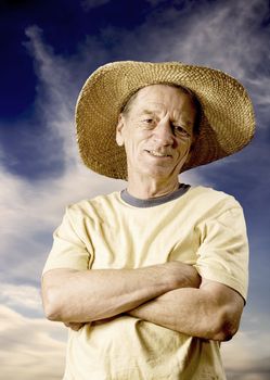 Senior man in a straw hat in front of cloudy sky
