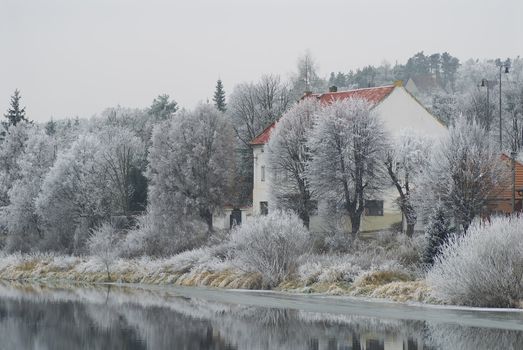 Winter landscape. The house on coast of the silent river.