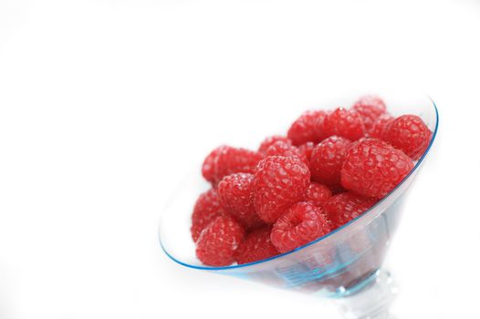 Raspberries in dessert bowl against white background.