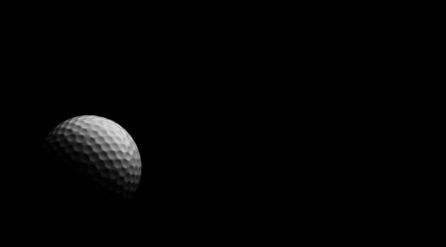 Golf ball under dramatic light, against black.