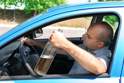 Drunk man sitting in drivers and holding a bottle alcohol