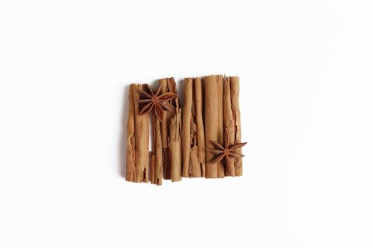 Anise sitting on row of cinnamon sticks.