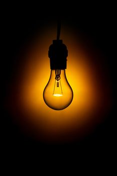 Glowing light bulb against black background.