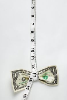 Dollar being squeezed by a tape measurer.
