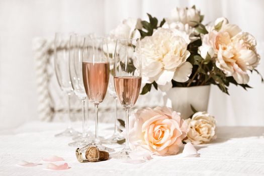 Two glasses filled with pink Champagne with flowers 