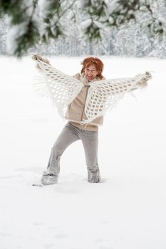 Happy red-haired woman having fun on winters day in forest.