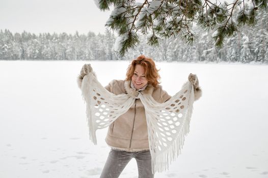 Happy red-haired woman having fun on winters day in forest.