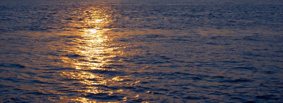 ocean's sunset with gold sunbeam over water