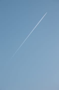 Jet flying high up and leaving vapor trail on a clear blue sky