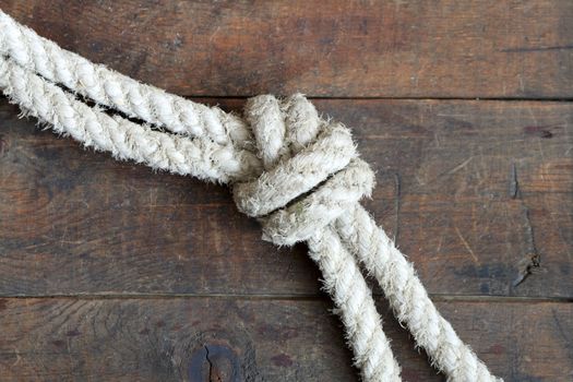 Two old ropes constrained with knots lying on wooden background