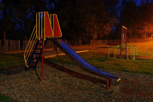 deserted colorful slide at a playground in Melrose, Scotland at night