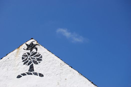 white gable with a symbol and blue sky
