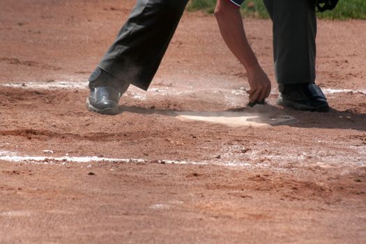 An umpire dusts off home plate.