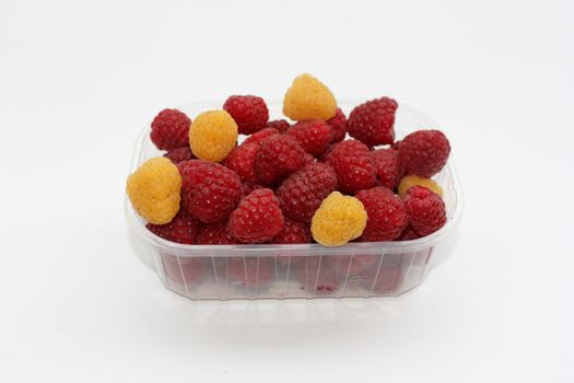 fresh raspberries with some yellow berries in a container, isolated