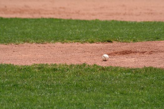 A baseball sitting in front of the pitchers mound.