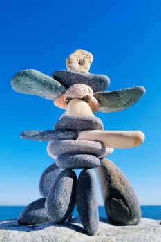 Symbolic figurines made of sea pebble on the background of sky