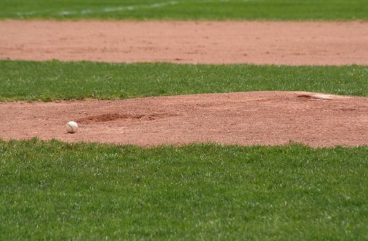 A baseball sitting in front of the pitchers mound.
