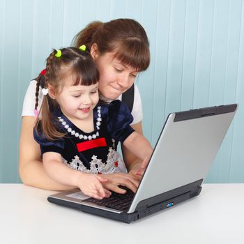 Mom teaches daughter to use a laptop