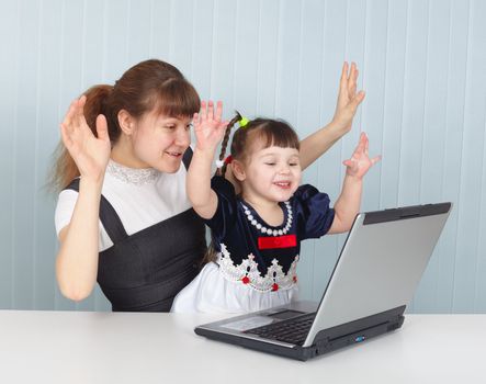 Daughter and mother playing with laptop at the table