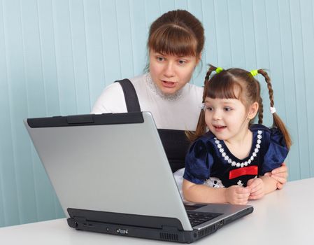 Young mother teaches daughter to use a computer