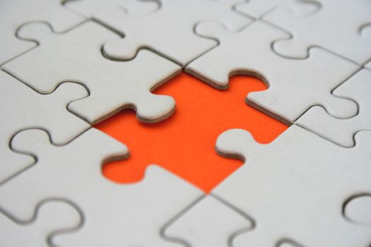 White jigsaw pattern with one mpty orange jigsaw puzzle element