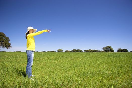 happy woman on a beautiful green meadow pointing something