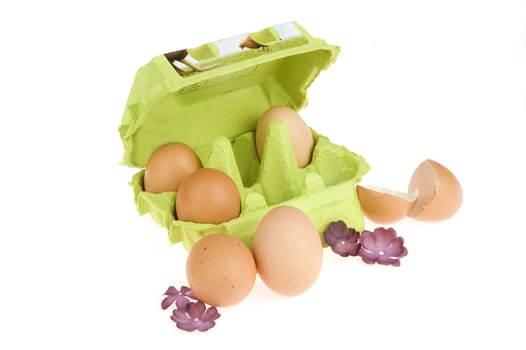 three eggs in a green box, two in front of box and egg shells